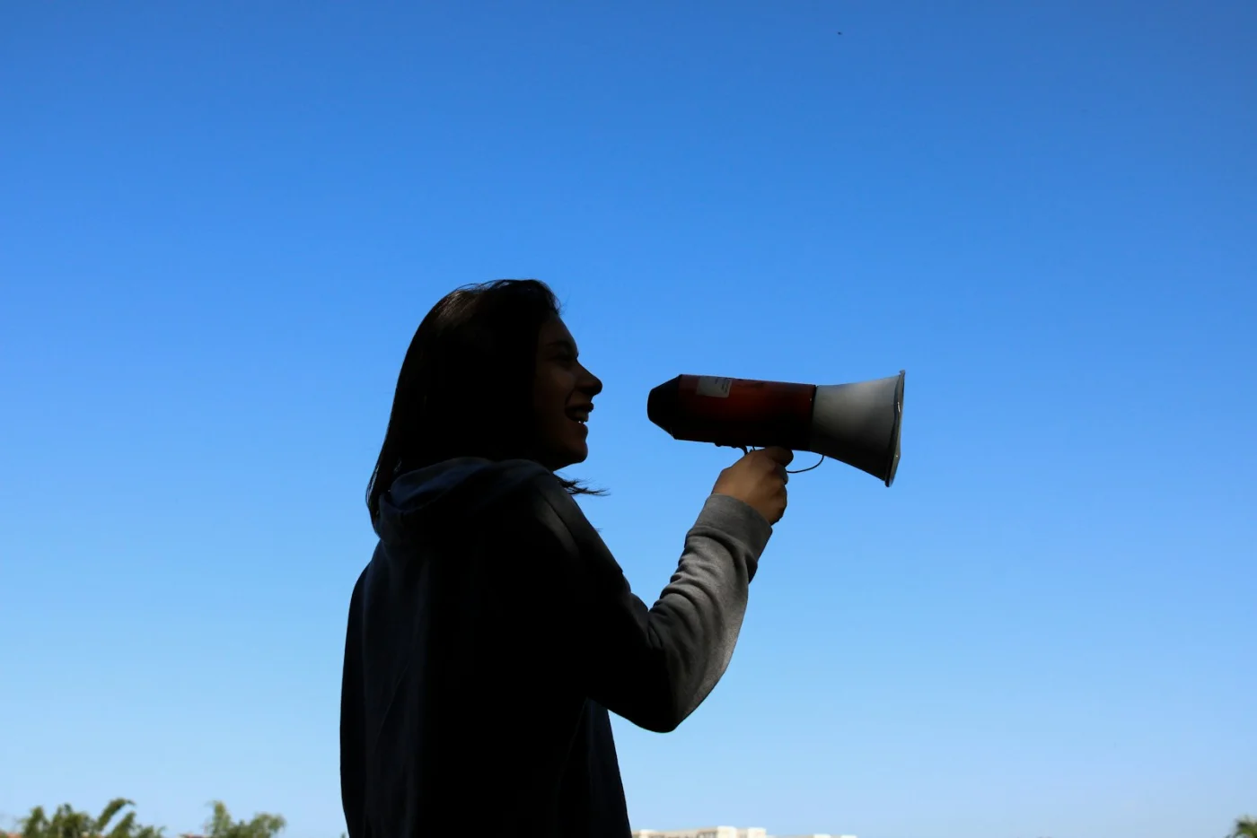 Silhouette of a person using a megaphone, representing important immigration announcements