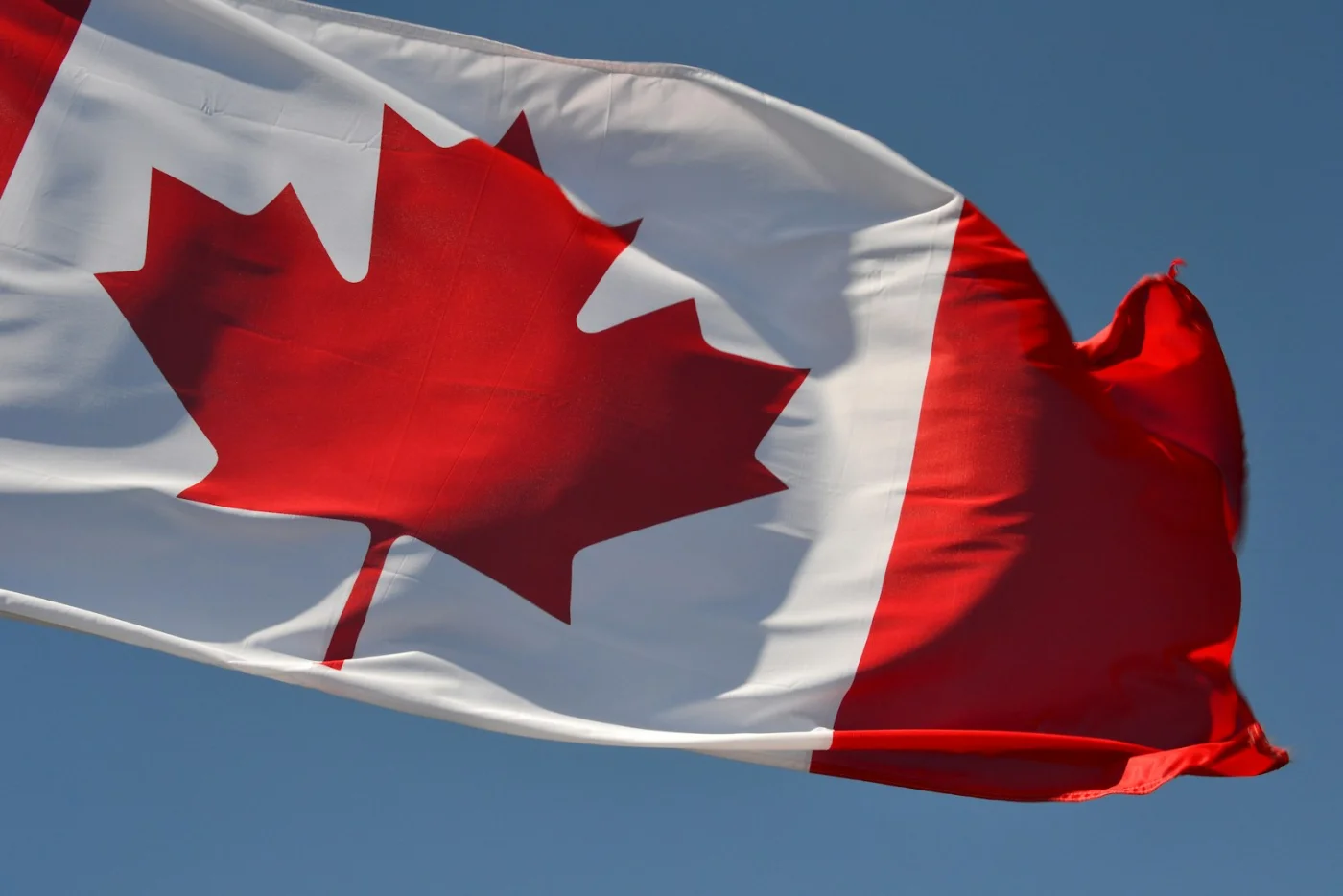 Canadian flag waving against blue sky, symbolizing new life in Canada