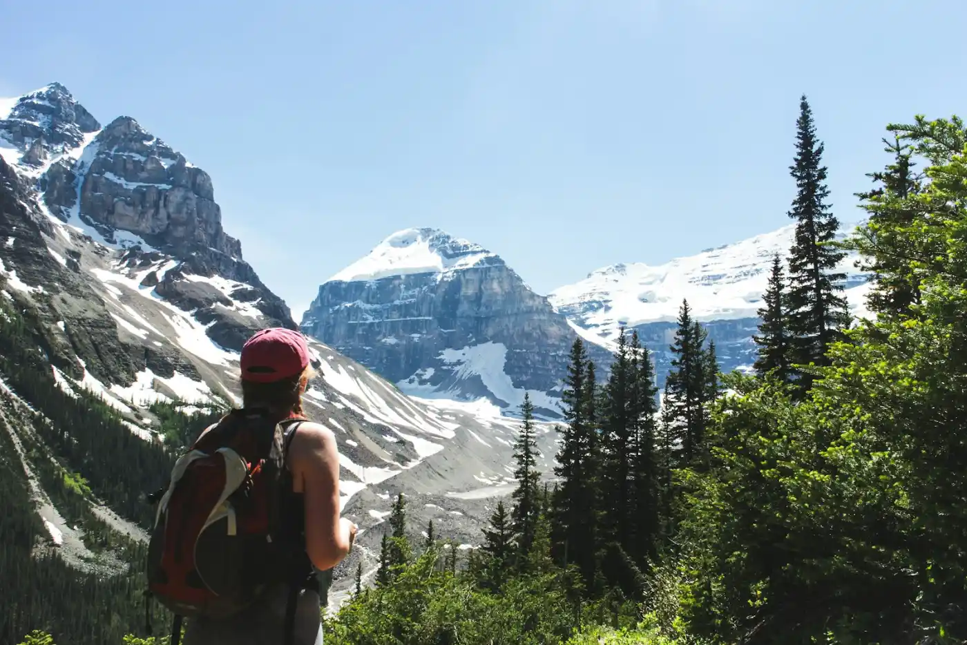 Young traveler on a Working Holiday Visa Canada trip, wrapped in the Canadian flag overlooking a turquoise lake