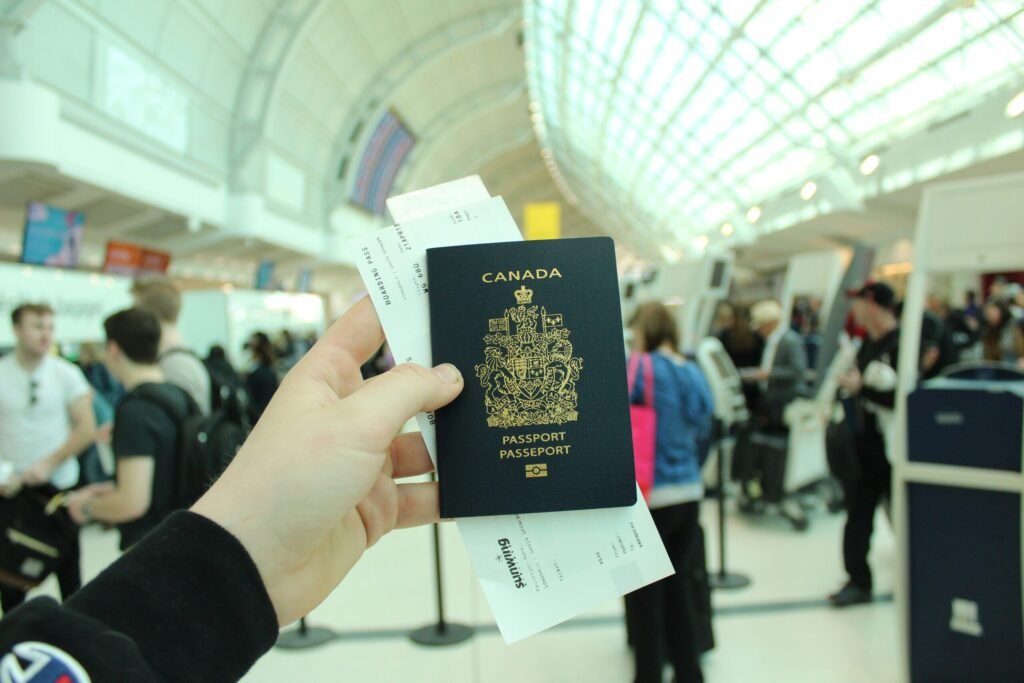 Traveler holding a Canadian passport at the airport after receiving an Express Entry invitation to apply